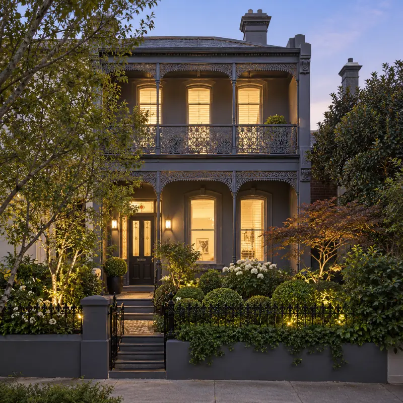 Dark Victorian period home in Prahran with ornate balcony, landscaped garden and warm evening lighting